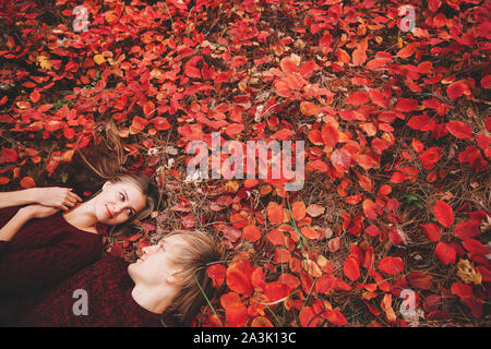 Couple portée dans les vêtements de style automne pulls famille regarder assis sur le paysage d'automne. Feuillage jaune couverte de forêt. Automne marcher à l'extérieur. Banque D'Images