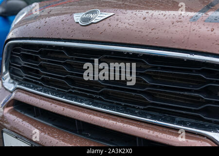 Close Up de Mini cooper logo avec des gouttes de pluie et la calandre avant voiture Mini cooper sur braun voiture garée dans la rue Banque D'Images