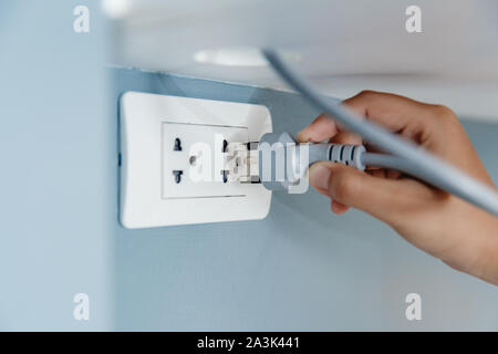 La main libre de brancher la prise murale d'électricité pour alimenter appareil électrique Banque D'Images