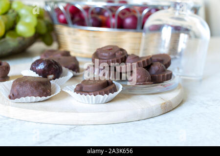 Des matières chocolat sucré bonbons aux framboises à l'intérieur de porter à la ronde sur le tableau blanc du Conseil de cuisine avec des fruits dans le panier en arrière-plan. Banque D'Images