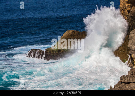 Vague se briser contre falaise, Nusa Penida island, Bali, Indonésie. Spray blanc dans l'air. Eau turquoise en premier plan. Banque D'Images