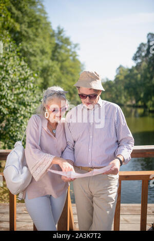 Couple élégant portant des lunettes de l'étude de la carte de park Banque D'Images