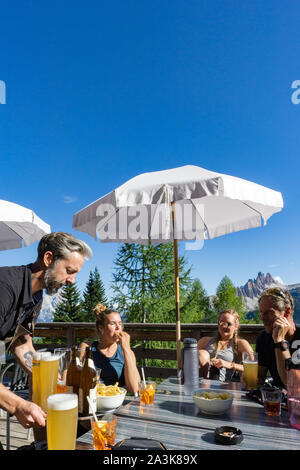 Cortina d'Ampezzo, Belluno / Italie - 3 septembre 2019 - femme d'escalade et leur guide de montagne se détendre dans un bar avec bière et chips après une dure ascension Banque D'Images