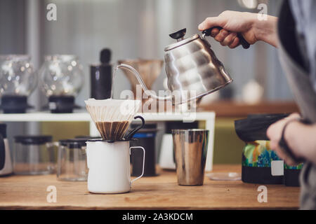 Au-dessus de café barista se déverse dans l'entonnoir. Tenir la main de Barista metal électrique avec de l'eau bouillante Banque D'Images