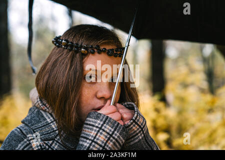 Fille de rousseur à tête rouge en automne parc jaune sous le parapluie. Banque D'Images