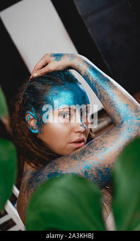 Portrait of a Beautiful woman posing comme dans la forêt sauvage. Woman with blue sparkles sur son visage. Les gens sont différents des autres. L'individualité Banque D'Images