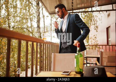 Bien habillé beau homme arabe à cigares fumée balcon de pub. Banque D'Images