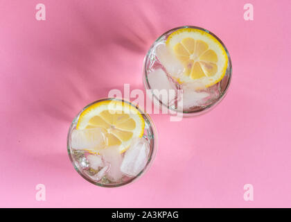 Deux verres d'eau froide avec les tranches de citron et de glace sur un fond de couleur pastel. Mode de vie sain. Des boissons rafraîchissantes. Banque D'Images