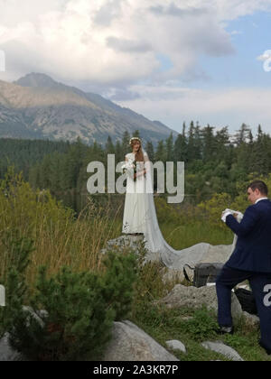 Une femme et un homme poser pour les photographies de mariage par le lac de Štrbské Pleso dans les Hautes Tatras, en Slovaquie. Septembre 2019. Banque D'Images
