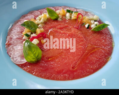 Close-up of a servi de restaurant espagnol rafraîchissante soupe gaspacho de tomates rouges, servi en plaque blanche et décoré avec des légumes frais et bas Banque D'Images