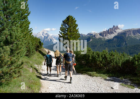 Les grimpeurs marchant sur une route dans un paysage de montagne Dolomites après une dure ascension avec une magnifique vue panoramique derrière eux des montagnes de l'Alta Badia Banque D'Images