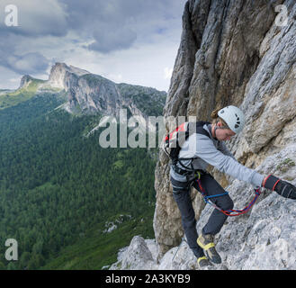 Un jeune grimpeur sur une via ferrata dans les Dolomites d'Alta Badia avec endommagé et chaussures cassé Banque D'Images