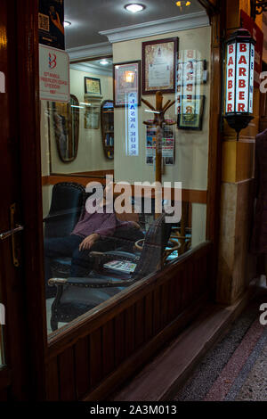 Istanbul : l'homme de dormir sur une chaise dans un salon de coiffure à l'intérieur de l'Cicek Pasaji, le passage des fleurs, galerie historique sur Istiklal Caddesi, une célèbre avenue Banque D'Images