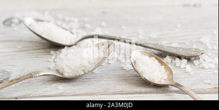 Cuillères à soupe de sel de mer sur une vieille table en bois Banque D'Images