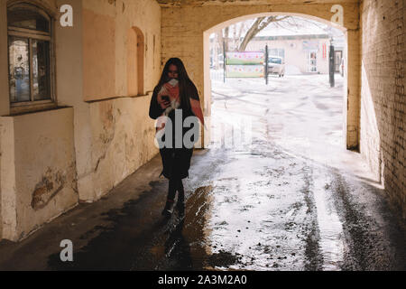 Young woman using smart phone tout en marchant à travers la ville pendant l'hiver en Banque D'Images