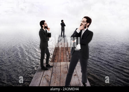 Trois projections d'un pensive businessman en costume et lunettes debout sur la jetée en bois qui va dans l'eau. Pensée et d'idée de la recherche co Banque D'Images