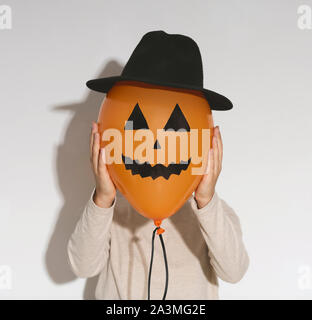Woman holding Jack o Lantern ballon en chapeau sur sa tête Banque D'Images