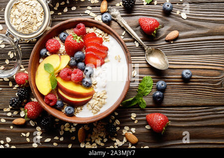 Mise à plat de fruits muesli sain avec des pêches amandes fraises et blackberry dans l'argile avec du yaourt Banque D'Images