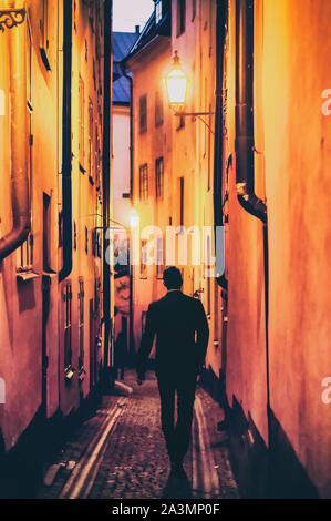 Silhouette d'un jeune homme en tenue de cérémonie marchant dans une ruelle à Stockholm Banque D'Images