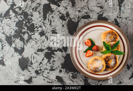 Petit déjeuner gastronomique - curd crêpes, crème glacée, fromage crêpes avec les fraises, la menthe et le sucre glace dans une assiette blanche. Focus sélectif. Vue d'en haut Banque D'Images