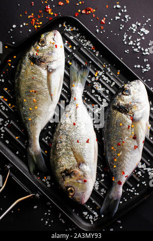 Matières premières fraîches Dorado poisson sur iron grill pan. Concept fruits de mer de la Méditerranée. La cuisine italienne. Coup de frais généraux, de mise à plat. Copier l'espace. La verticale Banque D'Images