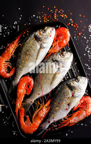 Poisson frais Dorado et crevettes géantes sur iron grill pan. Concept fruits de mer de la Méditerranée. La cuisine italienne. Coup de frais généraux, de mise à plat. La verticale Banque D'Images