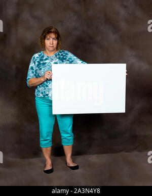 D'un coup vertical en colère ou concerné middle-aged Woman Holding a Blank Sign. Banque D'Images