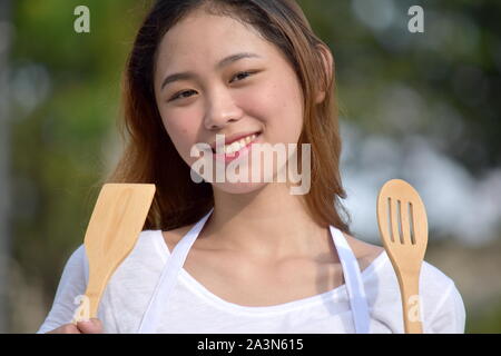 Smiling Filipina femme cuisinière avec ustensiles Banque D'Images