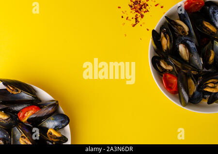 Fruits de mer italiens traditionnels. Soupe de moules à la vapeur dans le vin avec les tomates et piments sur fond jaune. Passage tourné, copy space Banque D'Images