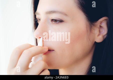 Spray nasal. Gros plan du visage de la belle jeune femme avec des gouttes. Close-up of female medical pulvérisation nasale dans le nez. Rhumes et grippe, guéris Banque D'Images