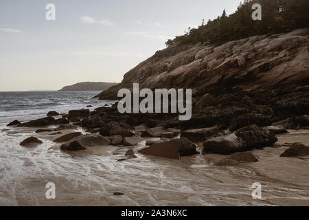 Coucher de soleil sur le littoral accidenté de la plage de sable fin lors d'une fraîche soirée d'Automne dans le parc national Acadia sur Mount Desert Island, dans le Maine. Banque D'Images