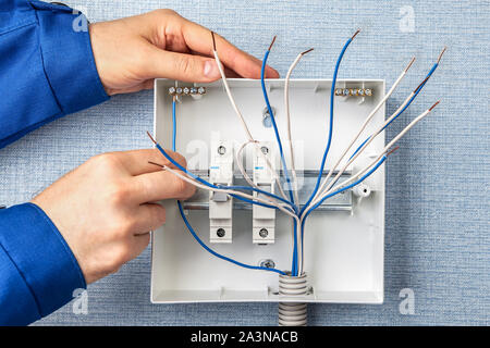 Technicien d'installation d'un nouveau standard téléphonique avec fusibles automatiques pour les fils électriques. L'installation de boîtes à fusibles dans un bâtiment résidentiel, un Banque D'Images