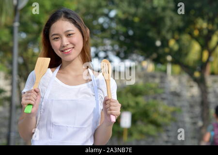 Happy Asian Female Chef cuisinier portant un tablier avec ustensiles Banque D'Images