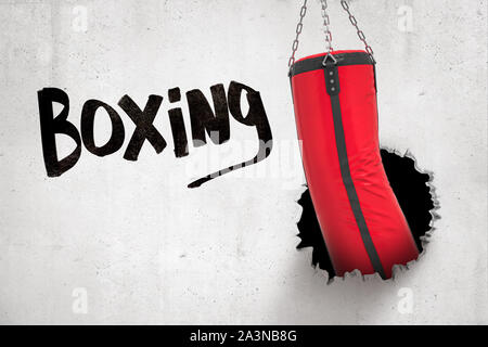 Le rendu 3D de sac de frappe rouge casser mur blanc avec 'Boxing' sign on white background Banque D'Images