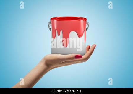 Femme hand holding pot de peinture rouge sur fond bleu Banque D'Images