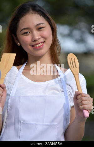 Belle femme cuisinière Divers Smiling avec ustensiles de cuisine Banque D'Images