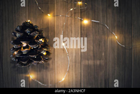 Pin (Pinus pinea) sur une table en bois avec des feux dans un flou d'arrière-plan flou. Selective focus sur une partie de la pomme. Banque D'Images