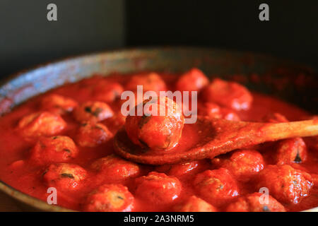 La cuisine italienne. Des boulettes à la sauce tomate dans une casserole sur fond sombre. Banque D'Images