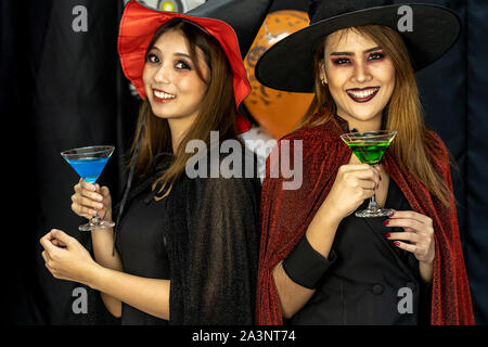 Deux jeunes adolescentes et adultes célébrer une fête d'Halloween carnaval Festival à Halloween costumes cocktail boire de l'alcool Banque D'Images