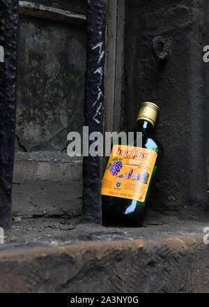 Une demi-bouteille de vin bon marché l'abeille Buckfast calé sur une vieille fenêtre sale ledge à Édimbourg, Écosse, Royaume-Uni, Europe Banque D'Images