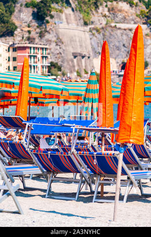 De nombreuses rayures bleu, rouge, blanc, Transats Parasols parasols, le repos des touristes sur la plage de Monterosso al Mare, Cinque Terre, Italie Banque D'Images