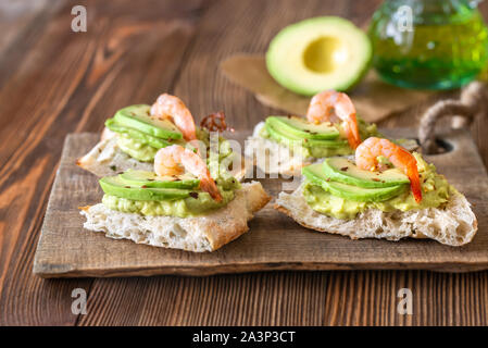 Des sandwichs avec de la guacamole, tranches d'avocat et les crevettes sur la planche de bois Banque D'Images