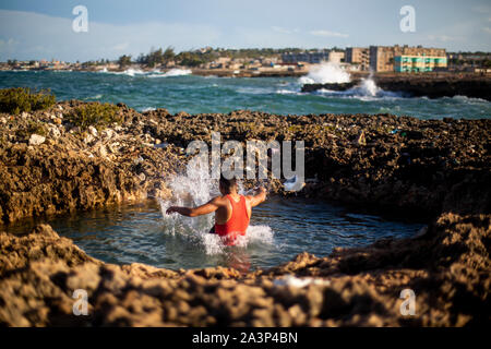 Un jeune homme passe dans l'eau à une plage à Gibara, une municipalité située dans l'Est de Cuba. Banque D'Images