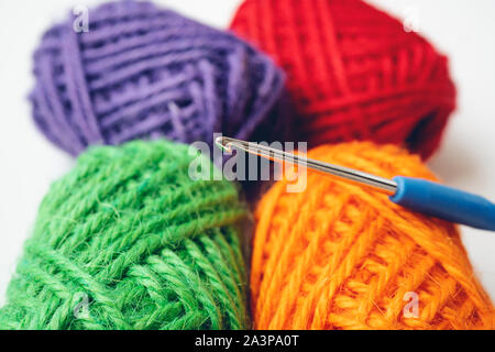 De l'artisanat et la couture concept - close up de boules colorées de la laine, des aiguilles à tricoter et corde de jute sur fond blanc avec copie espace libre Banque D'Images