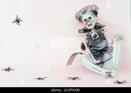 Le squelette en robe de mariage la mariée est assise contre le mur Banque D'Images