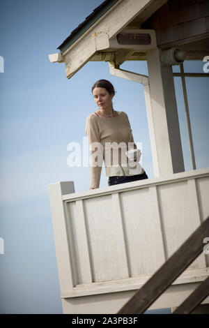 Jeune femme debout avec une tasse de thé sur un balcon par la mer. Banque D'Images