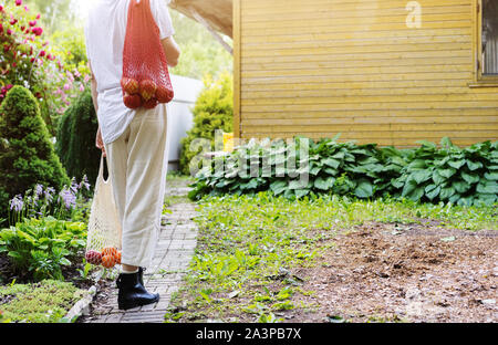 Une femme en pantalon blanc et des chaussures est debout sur l'avant du mur jaune Banque D'Images