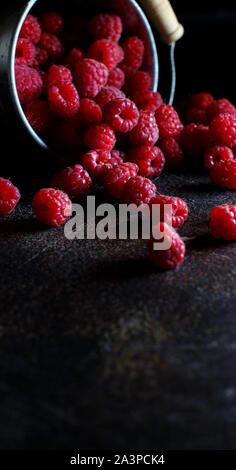 Framboises fraîches dans un petit seau en métal sur fond sombre Banque D'Images