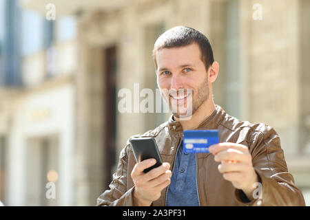 La consommation téléphone mobile et une carte de crédit vous regarde dans la rue Banque D'Images