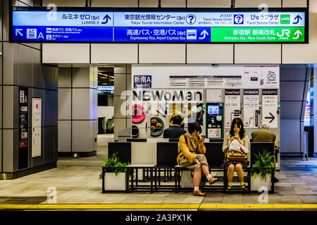 Les femmes se reposant sur le long banc de la gare de Shinjuku, Tokyo, Japon. Banque D'Images